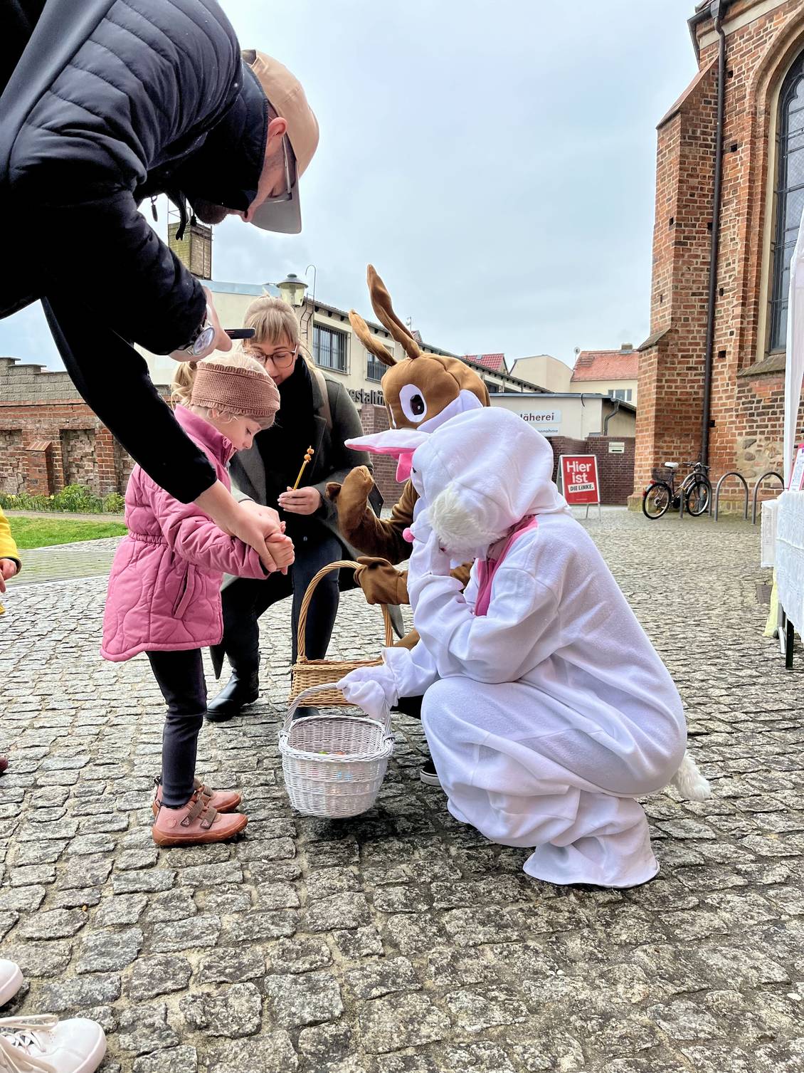 Das Foto zeigt ein Kind zusammen mit seinen Eltern und mit Menschen, die ein Osterhasenkostüm tragen.